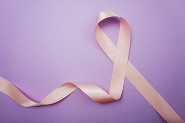 Pink ribbon breast cancer awareness on purple background