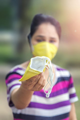 Beautiful Indian Woman Holding Pollution Mask outdoor for protect and to stop corona virus outbreak. Covid-19 Corona virus and Air pollution pm 2.5 concept