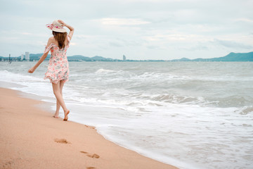 Asian woman in dress cloth walk relax on the beach with footprint.
