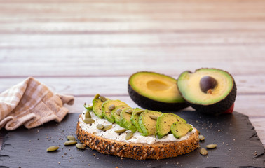 Sandwich or bruschetta light style with cheese and avocado - on a whole grain bread. Blank space for ads - healthy eat concept