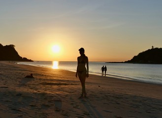 Silhouette of girl before sunset with orange sky at Nacpan beach, El Nido, Palawan, Philippines