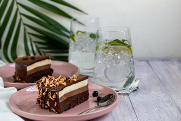 Holiday cake Three chocolates. Two white plates have two servings. On a light background. Birthday, holidays, sweets.