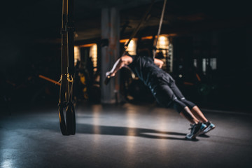 young man has crossfit workout with trx in modern gym