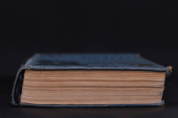 The closed book lies on a black background. Object for design. Interest in reading, learning