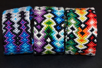 Colorful and multi-colored friendship bracelets handmade of embroidery bright floss and thread with knots isolated on black background