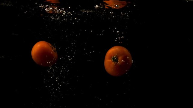 A Pair Of Tomatoes Still With A Small Stalk Unload Into The Water And Float. -wide shot