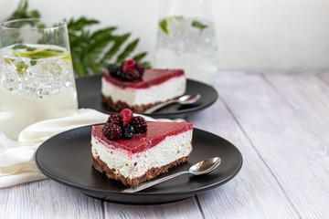 Cheesecake on two white plates, two servings. On a white background decorated with fresh berries. Birthday, holidays, sweets. I drink nearby.