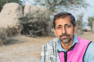 a vendor is selling candy on bicycle in a village and wearing pink jacket  