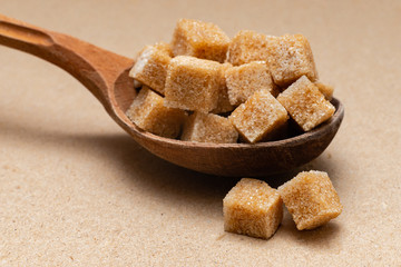 brown refined sugar in a wooden spoon on a craft paper background