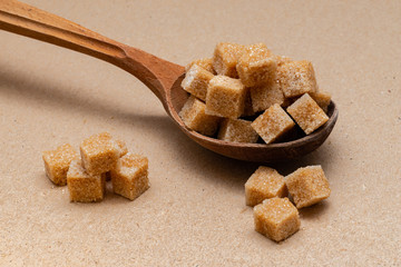 brown refined sugar in a wooden spoon on a craft paper background