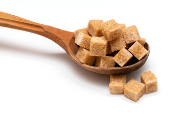 brown refined sugar in a wooden spoon on a white background