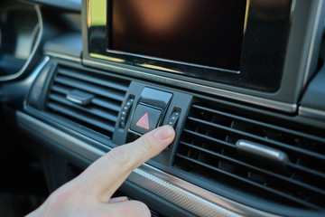 Obraz premium A man in a modern car. Hand turns the level of the air conditioner.