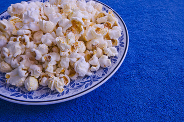 Ceramic dish of new popcorn on blue floor
