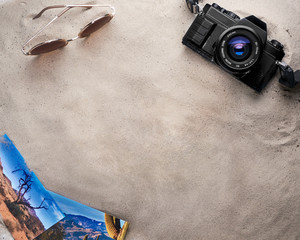 Camera, sunglasses and photos on sand background, perfect for travel