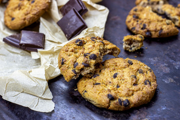 Freshly baked American chocolate chip cookies on rustic black metal table background.