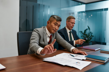 Stop. Asian businessman in formal wear don't want to sign contract while having a meeting with partners in the modern office