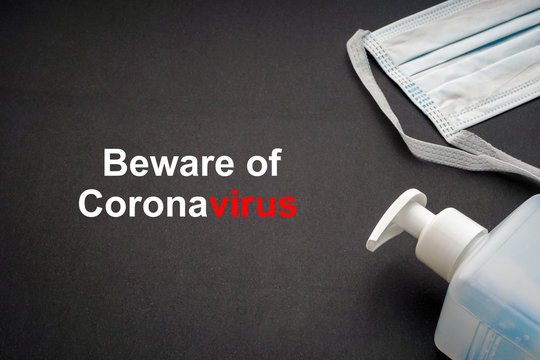 BEWARE OF CORONAVIRUS text with antibacterial soap sanitizer and protective face mask on black background. Covid-19 or Coronavirus Concept