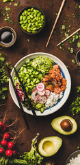 Healthy lunch. Flat-lay of salmon poke bowl or sushi bowl with various vegetables, greens, sushi...