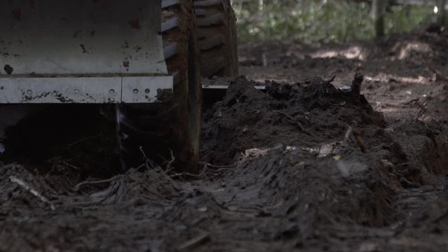 Close up shot of Road leveling motor grader on bad forest road at work. Excavator scraping dirt making a new road in a forest area. Process for resurfacing dirt road is same.