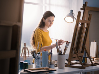 Young creative painter working with a lamp in the studio