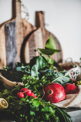 Vegan, vegetarian, balanced diet foods. Fruit, vegetables, nut, greens over grey concrete kitchen counter with grey wall background, selective focus, close-up. Healthy, clean eating