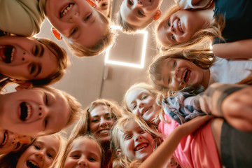 Simply happy. Group of positive boys and girls with their female dance teacher. Bottom view of happy children smiling at camera while standing in the dance studio