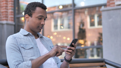 African Man Using Smartphone Sitting Outdoor