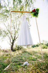 white wedding dress hanging on a wooden bar. morning of the bride
