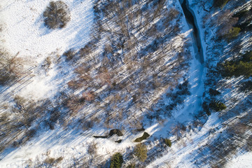 Beautiful Sunny landscape with forest, snow and frozen river. Aerial photography from a drone