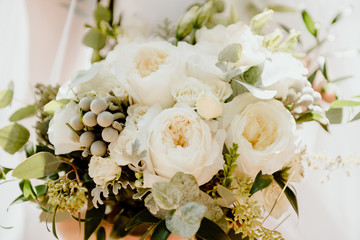bridal bouquet in hands close-up on a background of a wedding dress
