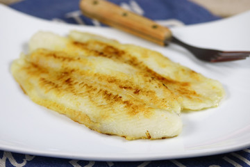 filet de tilapia en train de cuire dans une assiette
