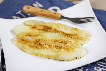 filet de tilapia en train de cuire dans une assiette