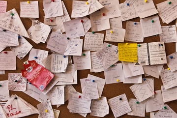 Post-it notes sticked chaotically on the wall - busy concept. in different languages