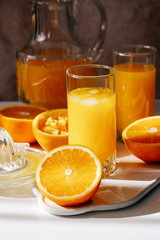 freshly squeezed orange juice in a glass, juicy cut oranges, sunny morning