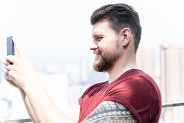 Profile of a man making a selfie with a city in the background