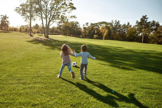 Relaxing weekend. Two kids playing with a ball on meadow
