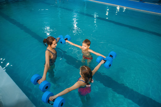 Children swimming group, workout with dumbbells