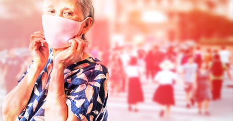Portrait of old woman wearing mask and feel sadness because of an epidemic virus with blurred people in red zone , Concept Prevention of covid-19