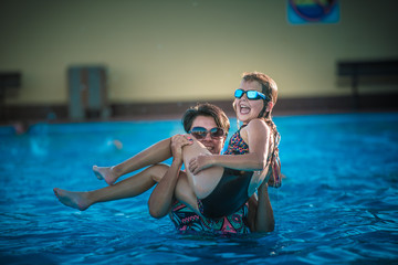 Obraz na płótnie Canvas Summer camp, szczęśliwa mama z córką pływa i bawi się na basenie w wodzie latem