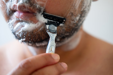 Young man removing mustache by shaving from his face.