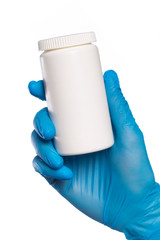 Surgeon's hand in a blue medical glove holds a can with pills. Isolated on white background.