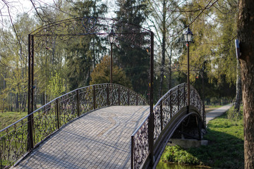 Beautiful bridge on a background of a green park and a house. European landscape.