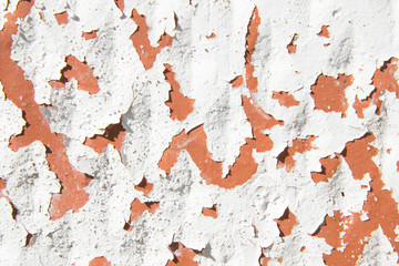 Background from one old vintage brick of red color with pieces of fallen off white paint (whitewash). Close-up. Cracked retro texture