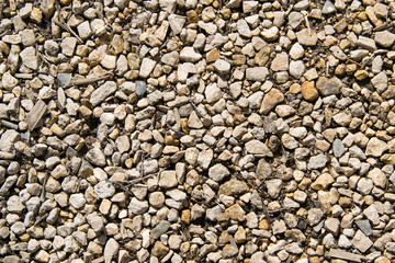 Background of dirty small gravel with light garbage. The texture of white and yellow crushed stone.
