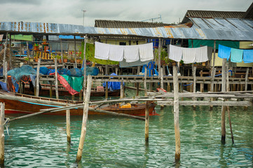 Fototapeta na wymiar Picturesque ancient fisher harbor with wooden structure on stilt. Drying linen and fishnets.