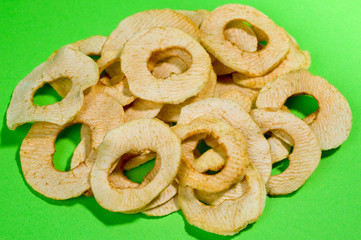 Chips from dried apples, sliced in thin circles. Photographed on a green background. Background for healthy eating and vegetarianism.