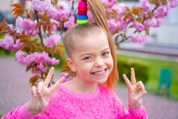 Cute child girl holding sakura blossom. Sakura Cherry Blossom Festival. Comic grimace, funny...