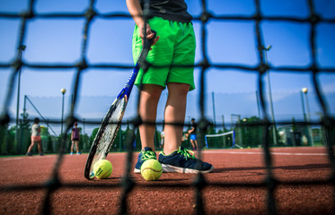Fototapeta summer camp, Little tennis player on a blurred green background obraz