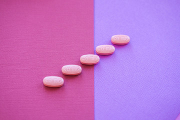 Heart pills. Medical tablets on pink background.