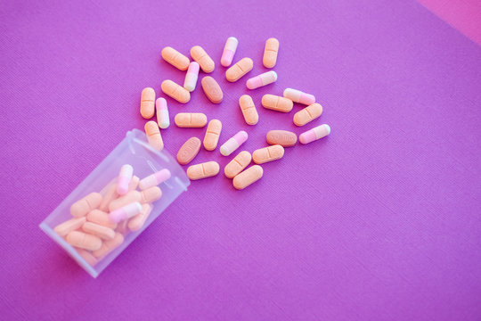Heart pills. Medical tablets on pink background.